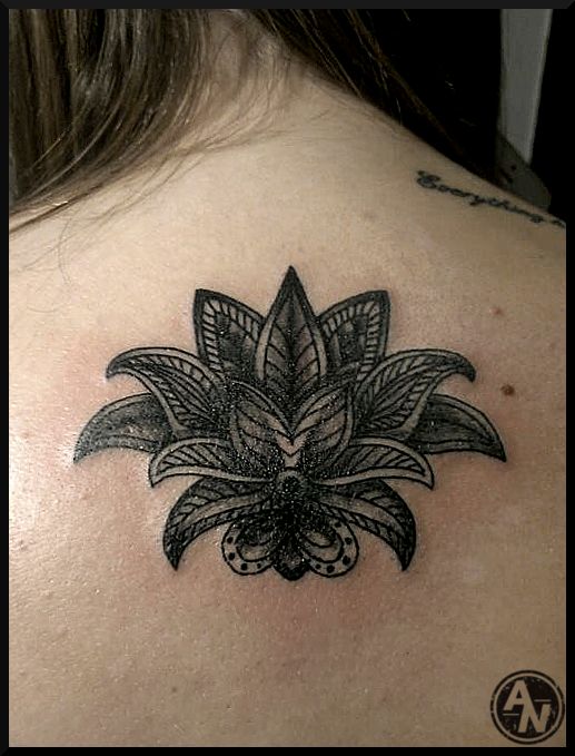 a black and white photo of a woman's back shoulder with a flower tattoo on it