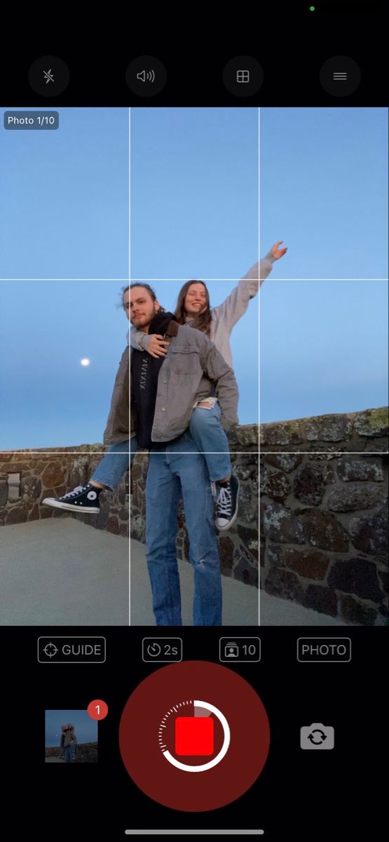 two people standing on a bridge with their arms in the air and one person taking a photo