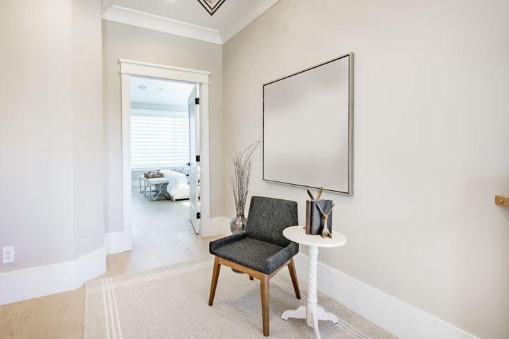 a chair sitting in the middle of a hallway next to a mirror and table with vases on it