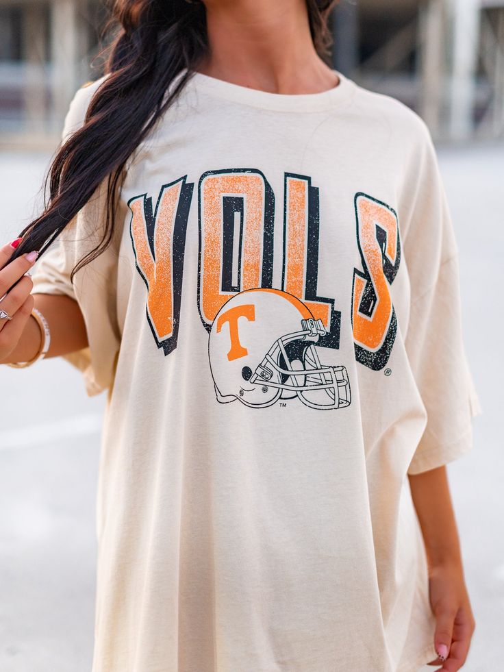 Get your game on with the Vols Helmet Fade Oversized Tee! This officially licensed shirt gives you an old school look while showing your love for the University of Tennessee. With a quirky style and playful tone, this tee is perfect for any true fan. Go Vols! Throwback Crew Neck Top For Game Day, Throwback Graphic Print Tops For Football Season, Retro Cotton T-shirt With Team Logo, Throwback Graphic Print Top For Game Day, Retro Short Sleeve Tops With Team Logo, Vintage Graphic T-shirt For Football Season, Vintage Graphic Print Football T-shirt, Vintage Graphic Print T-shirt For Football Season, Retro Oversized T-shirt For College