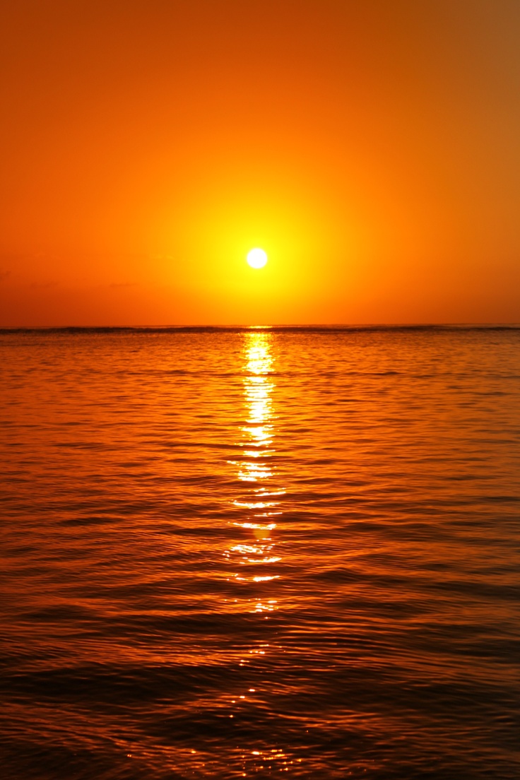 the sun is setting over the ocean with calm water