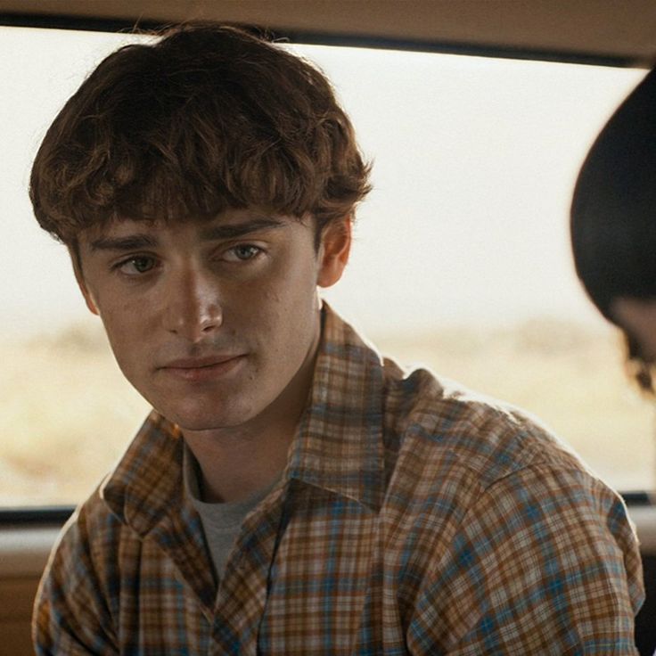 a young man sitting in the back seat of a car