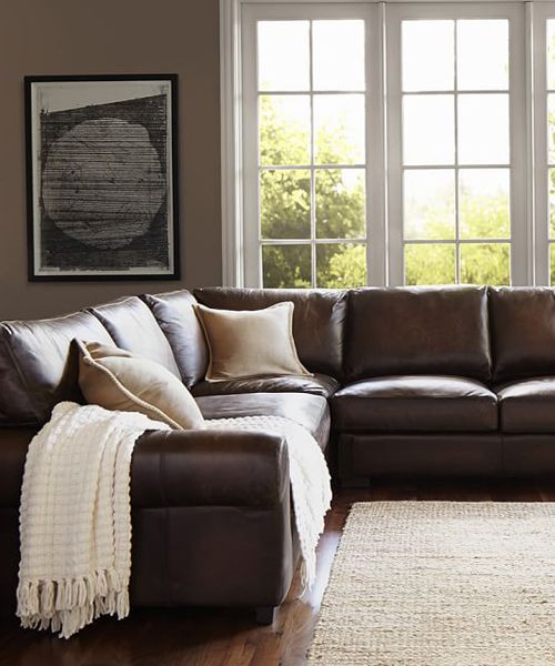 a living room scene with focus on the couch and large window in the back ground