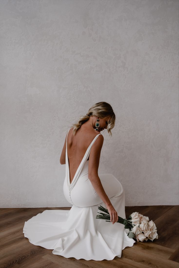 a woman in a white dress sitting on the floor with her back to the camera