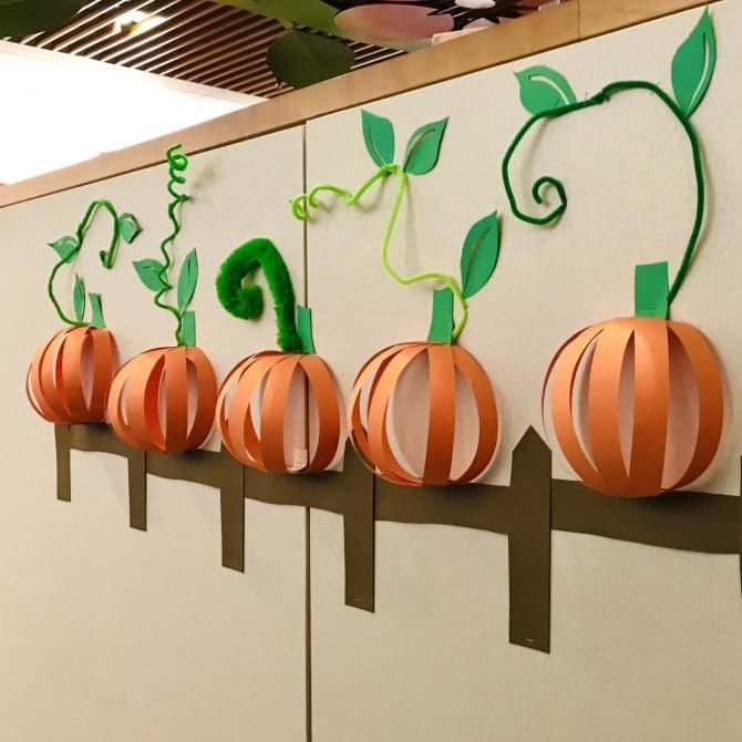 paper pumpkins are lined up on the wall