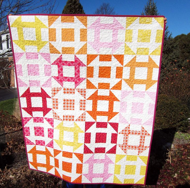 a person holding up a colorful quilt