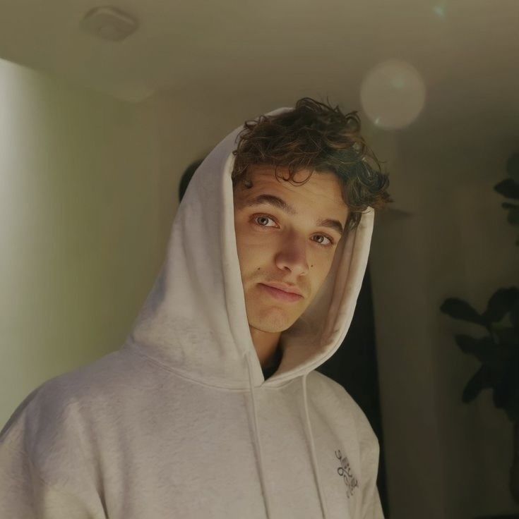 a young man in a white hoodie looking at the camera with an intense look on his face