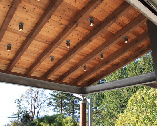 a covered porch with lights on the ceiling and trees in the backgroung