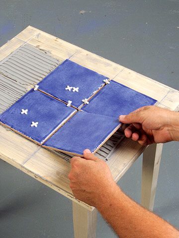 a person that is making something out of some kind of blue material on a table