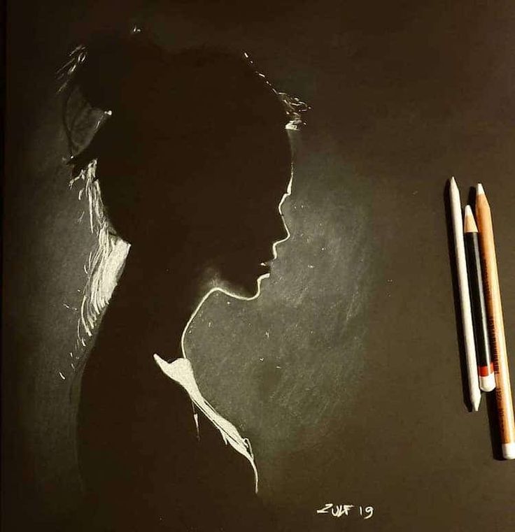 a drawing of a woman's profile on a blackboard with two pencils next to it