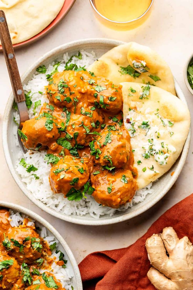 two plates filled with meatballs and rice on top of a table next to other foods