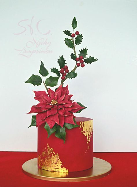 a red and gold decorated cake with holly on top