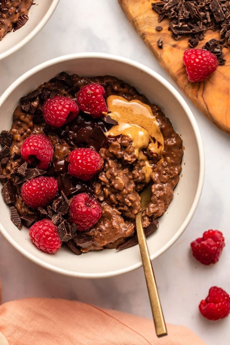 two bowls filled with chocolate oatmeal and raspberries