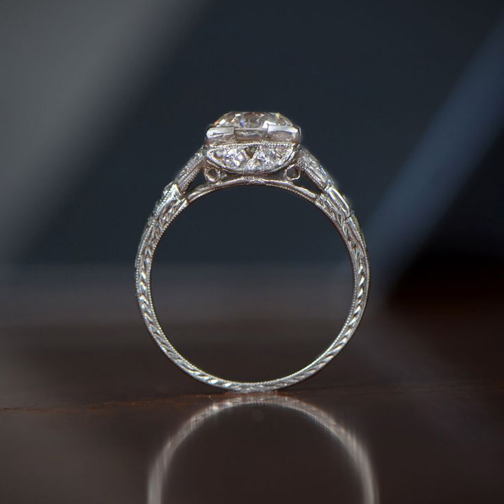 The Narbonne Ring showcases a lively old European cut diamond in the center, adorned by fine openwork filigree, and accented with diamonds. This antique ring was handcrafted circa 1920 in platinum. The center antique diamond weighs 1.44-carats, K color, and SI1 clarity. Antique Cushion Cut Single Diamond Rings, Antique Cushion Cut Ring With Single Cut Diamonds, Antique Cushion Cut Rings With Single Cut Diamonds, Heirloom Cushion Cut Diamond Ring, Heirloom Cushion Cut Diamond Ring With Single Cut Diamonds, Oval Rose Cut Diamond Jewelry For Vintage Events, Antique Platinum Cushion Cut Jewelry, Vintage Diamond Jewelry With Center Stone, Heirloom Diamond Ring With Cushion Cut