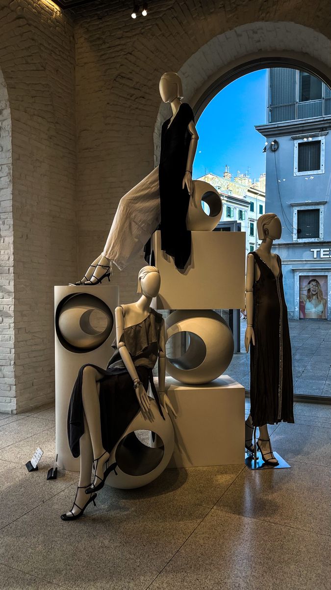 three mannequins are sitting on display in front of an arched window,