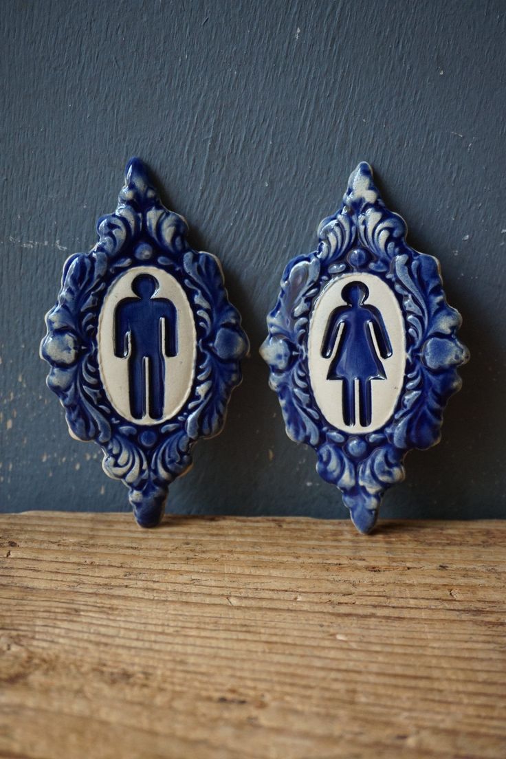 two blue and white ceramic wall hangings with an image of a man and woman