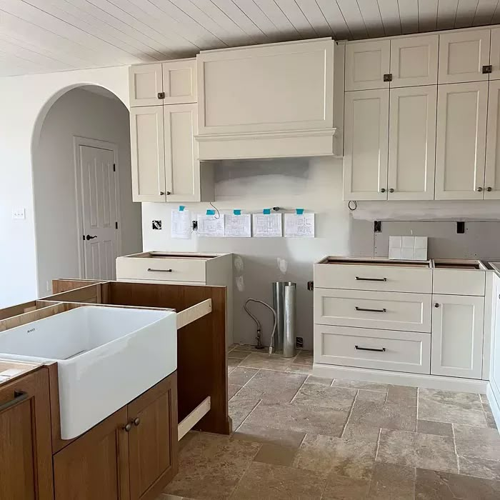 an empty kitchen with white cabinets and wood flooring is pictured in this image from the front view