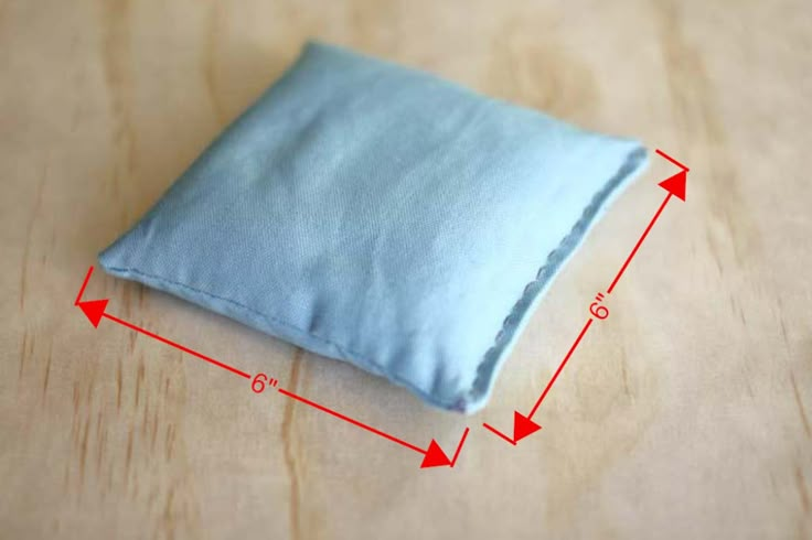 a small blue pillow sitting on top of a wooden table next to a measuring tape