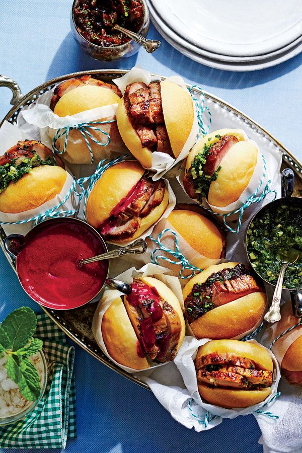 a platter full of hot dogs and condiments on a blue table cloth