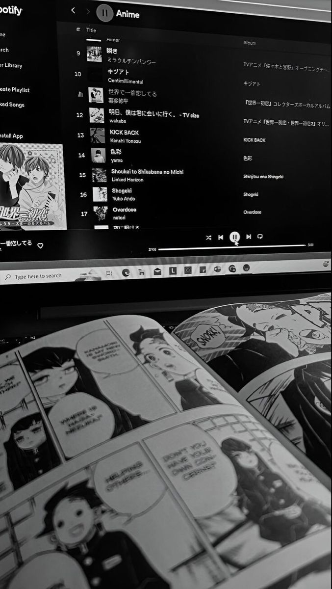 an open book sitting on top of a laptop computer next to a desktop monitor with comic pages