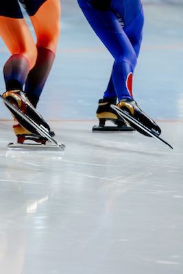 two people are skating on the ice with their feet in the air and one is wearing skis