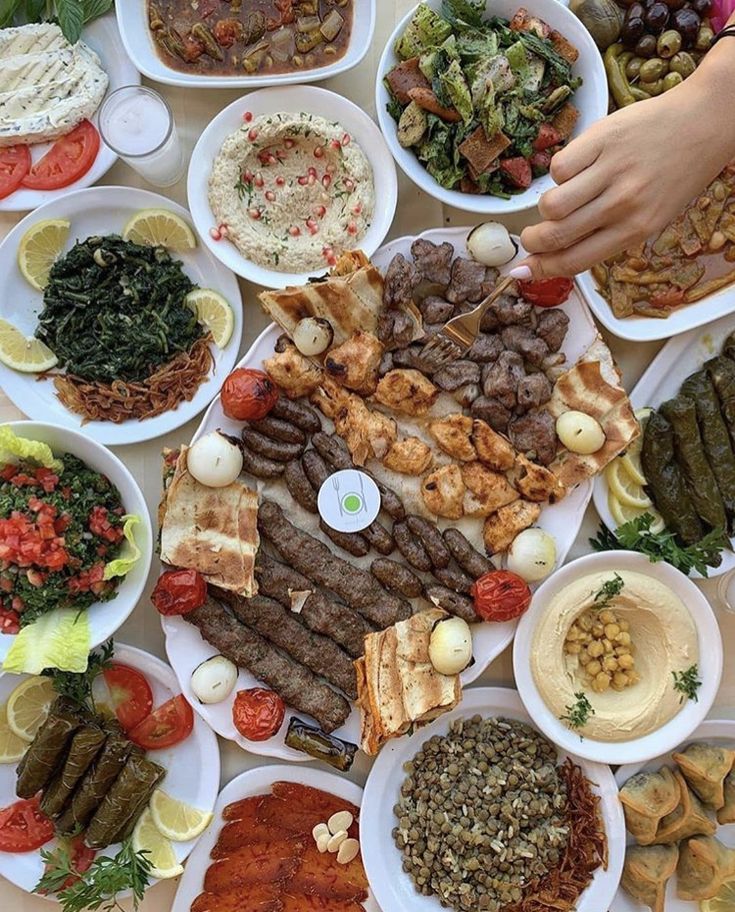 a table topped with lots of plates filled with different types of meats and veggies