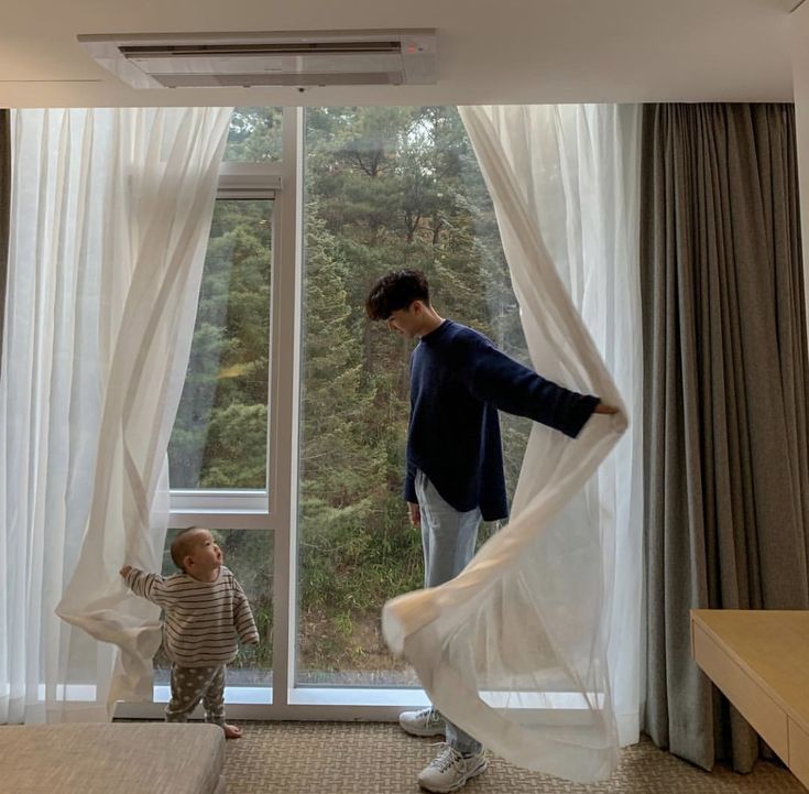 a man standing in front of a window next to a little boy