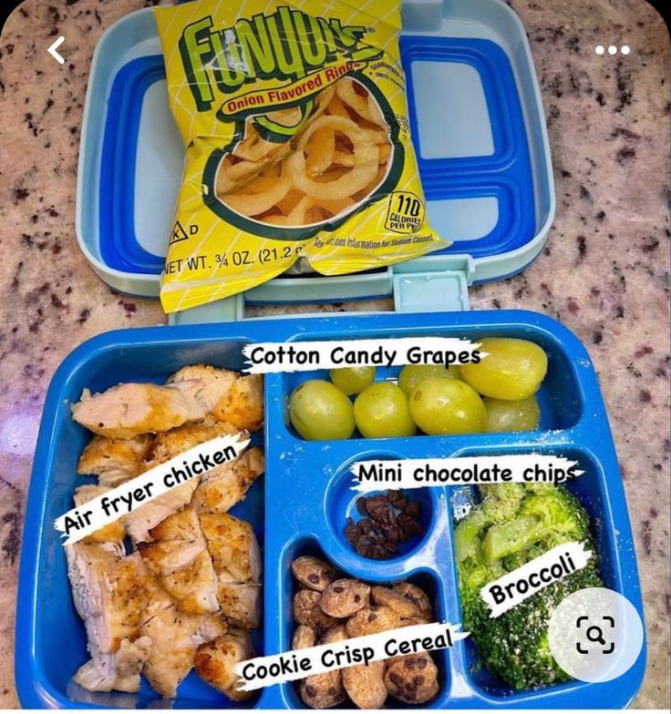 a lunch box with grapes, chicken, broccoli and other foods in it