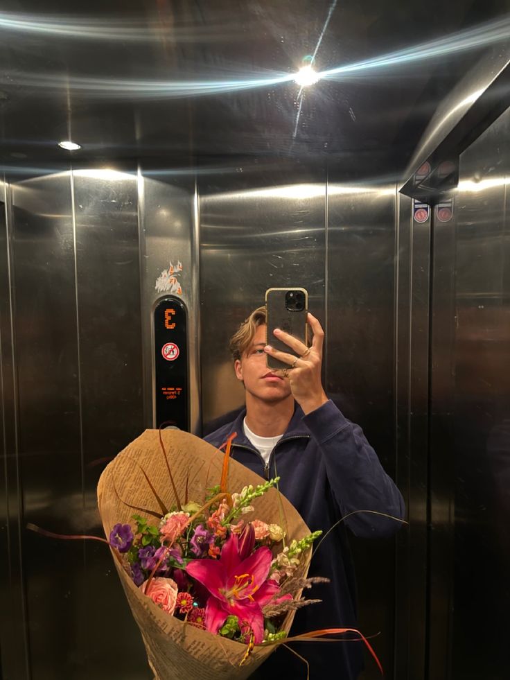 a man taking a selfie while holding a bouquet of flowers