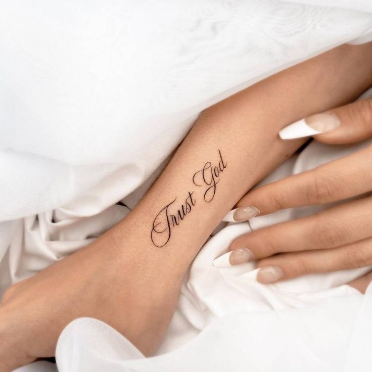 a woman's foot with the word trust god tattooed on her left arm and right hand