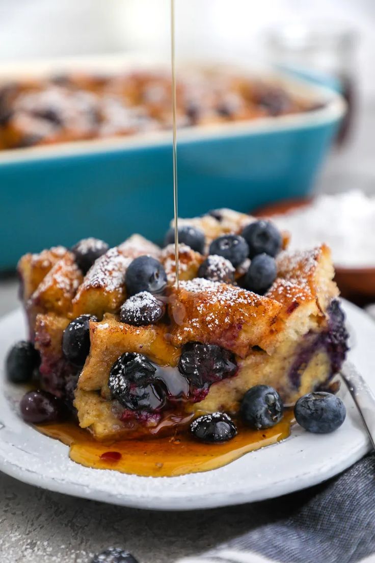 blueberry french toast with syrup being drizzled over it on a plate