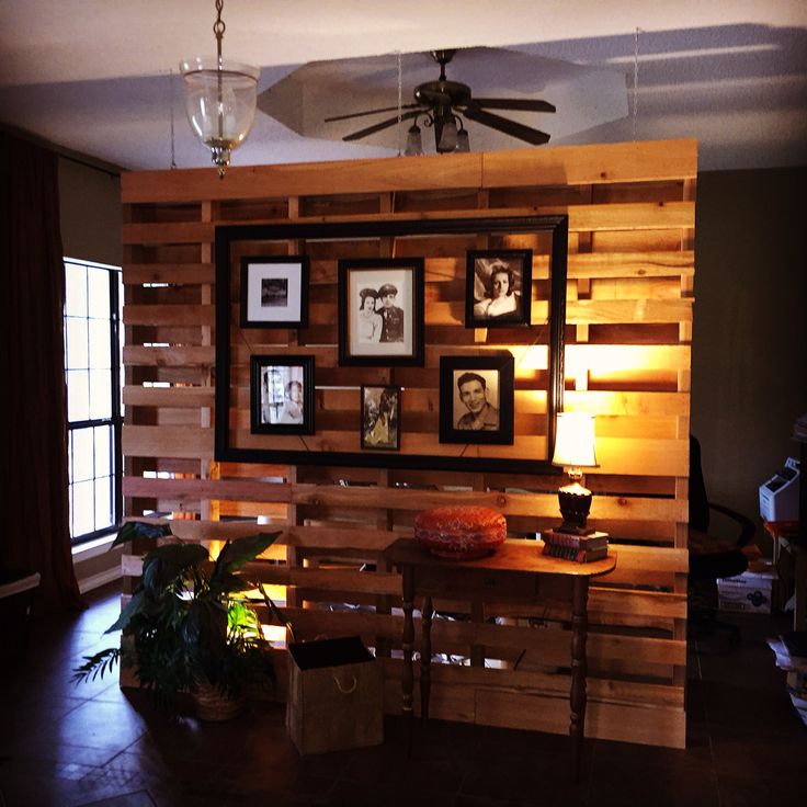 a living room with wood paneling and pictures on the wall, along with a ceiling fan