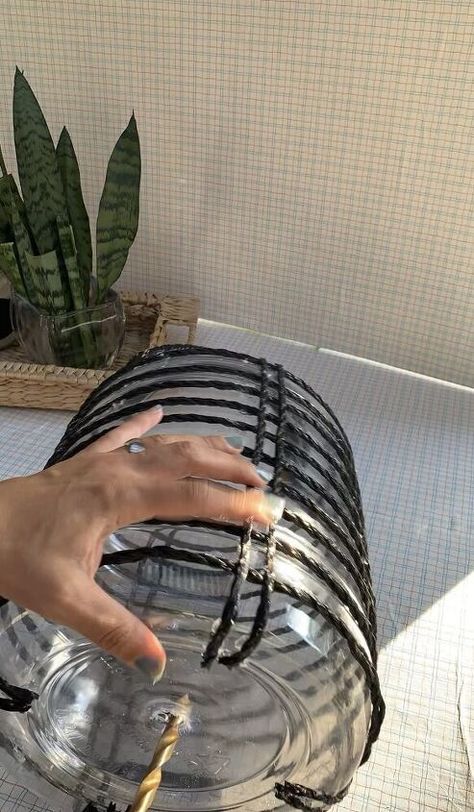 a hand reaching for something in a glass bowl on a table next to a potted plant