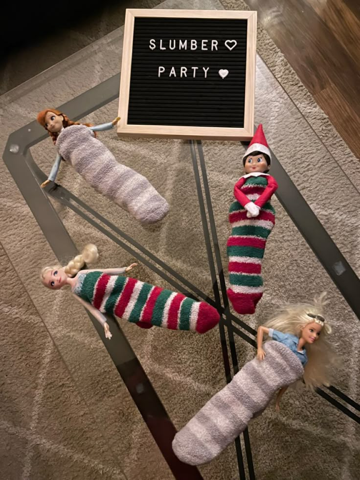 three sock dolls are laying on the floor next to a sign that says slumber party