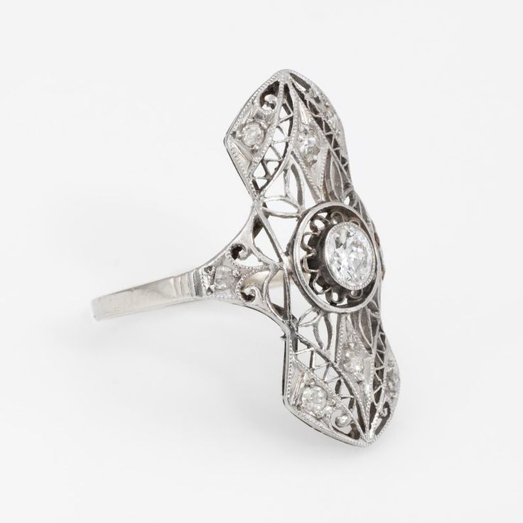 This is part of Chairish’s Fine Jewelry assortment.  Finely detailed vintage Art Deco era ring (circa 1920s to 1930s), crafted in 14 karat white gold.   Centrally mounted estimated 0.20 carat old European cut diamond is accented with 8 x estimated 0.02 carat old single cut diamonds. The total diamond weight is estimated at 0.36 carats. The centre diamond is estimated at H-I colour & SI2 clarity. The side diamonds are estimated at J-L colour and I1 clarity.   The ring features lacy filigree detai Victorian Platinum Diamond Ring With Hallmark, Victorian Platinum Diamond Ring Hallmarked, Estate Rose Cut Diamond Jewelry For Anniversary, Estate Jewelry With Rose Cut Diamonds For Anniversary, Vintage Platinum Rings Hallmarked, Art Deco White Gold Engraved Ring, Vintage Hallmarked Platinum Rings, Oval Platinum Diamond Ring With Filigree, Platinum Vintage Filigree Ring For Formal Events