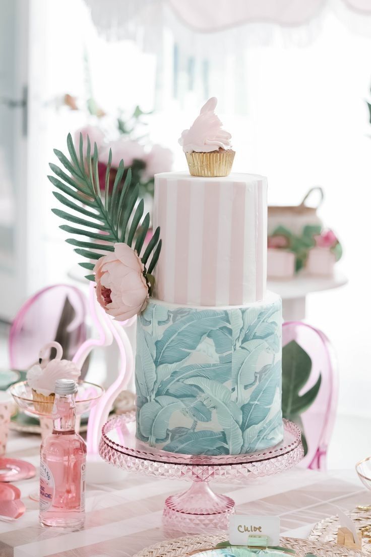 a three tiered cake sitting on top of a table next to pink and white plates