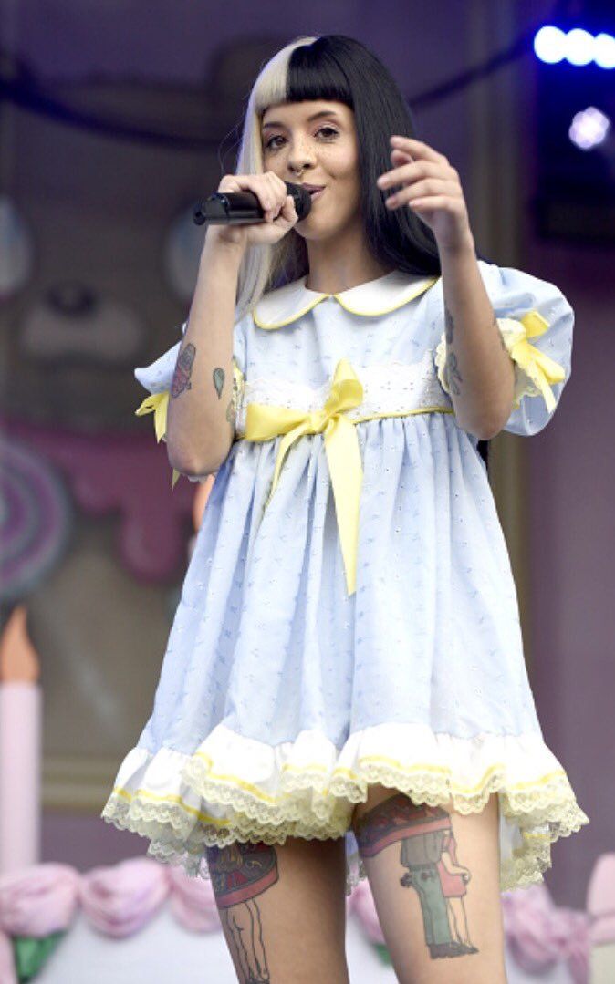 a woman with tattoos on her arms and legs, wearing a blue dress while holding a microphone