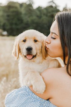 a woman holding a puppy in her arms and kissing it's face on the cheek