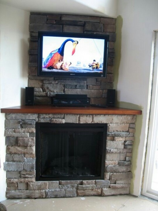 a flat screen tv mounted on top of a stone fireplace