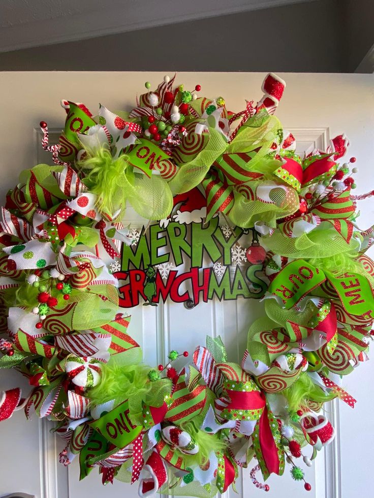 a christmas wreath is hung on the front door with green and red ribbons, candy canes, and decorations