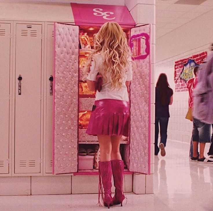 a woman standing in front of a pink locker filled with food and wearing knee high boots