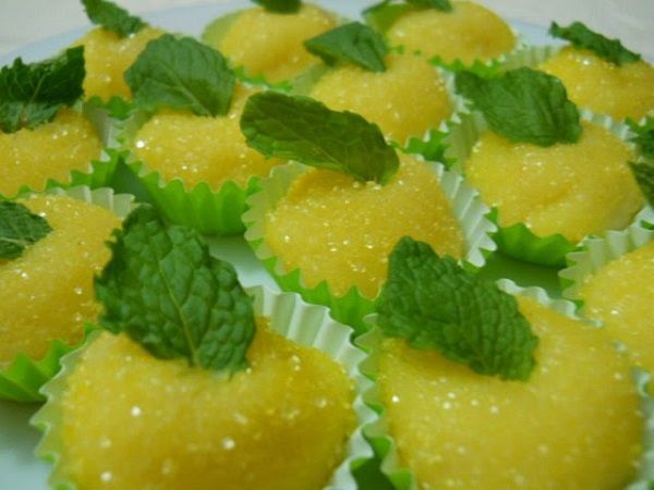 small desserts are arranged on a plate with green leaves and water droplets around them