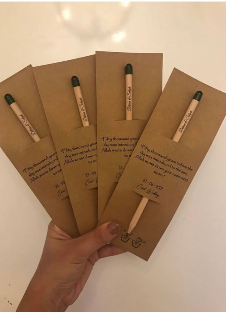 four brown envelopes with writing on them are held by a person's hand