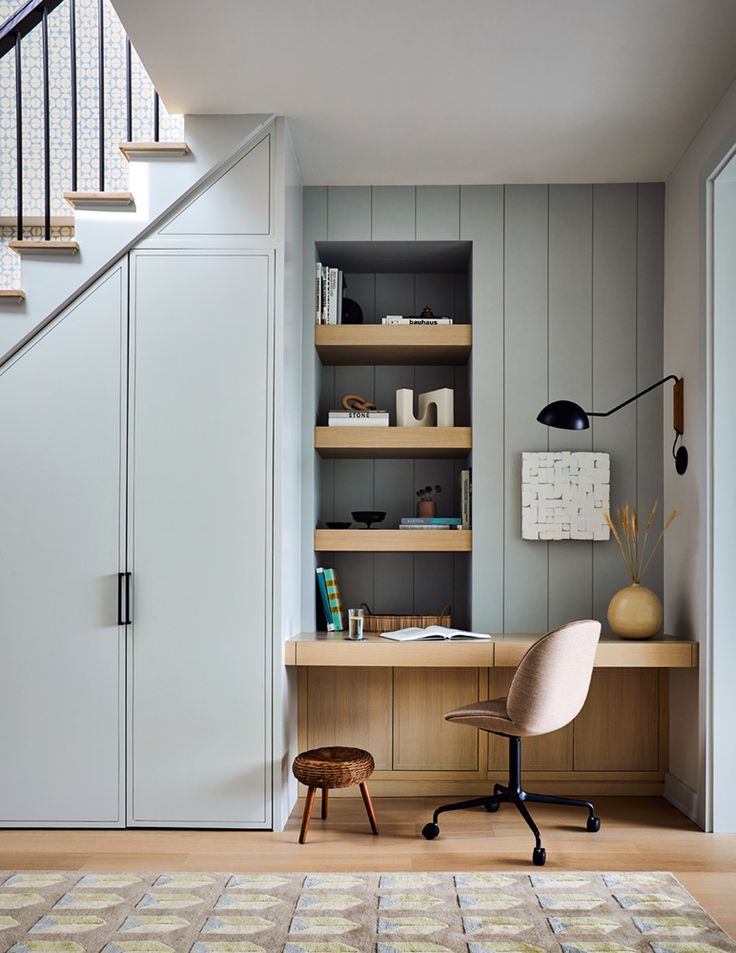 a room with a chair, bookshelf and stairs in the wall next to it