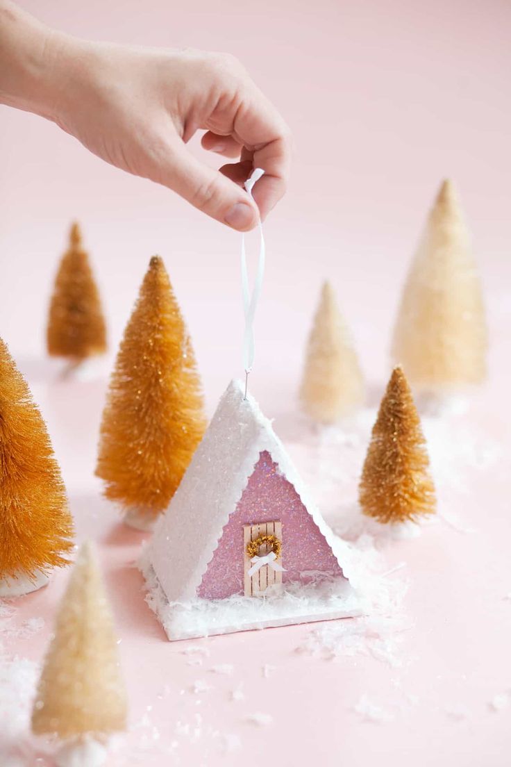 someone is decorating small houses with fake trees in the shape of houses and snow