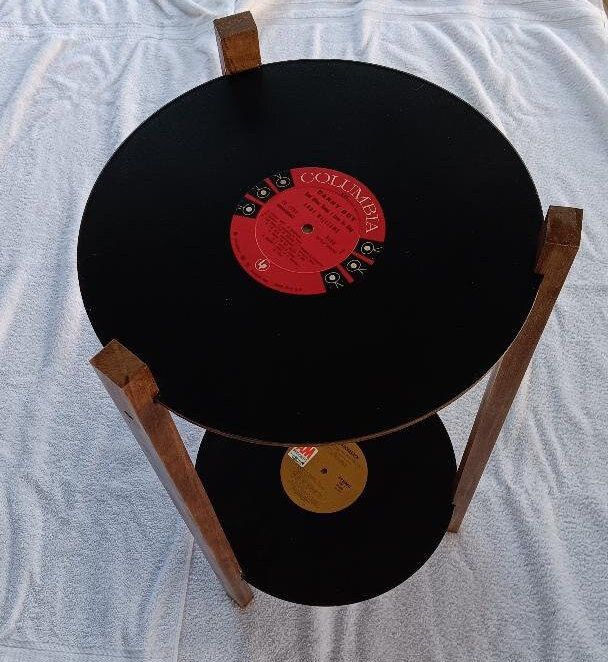 an old record sitting on top of a wooden table next to a white cloth covered bed