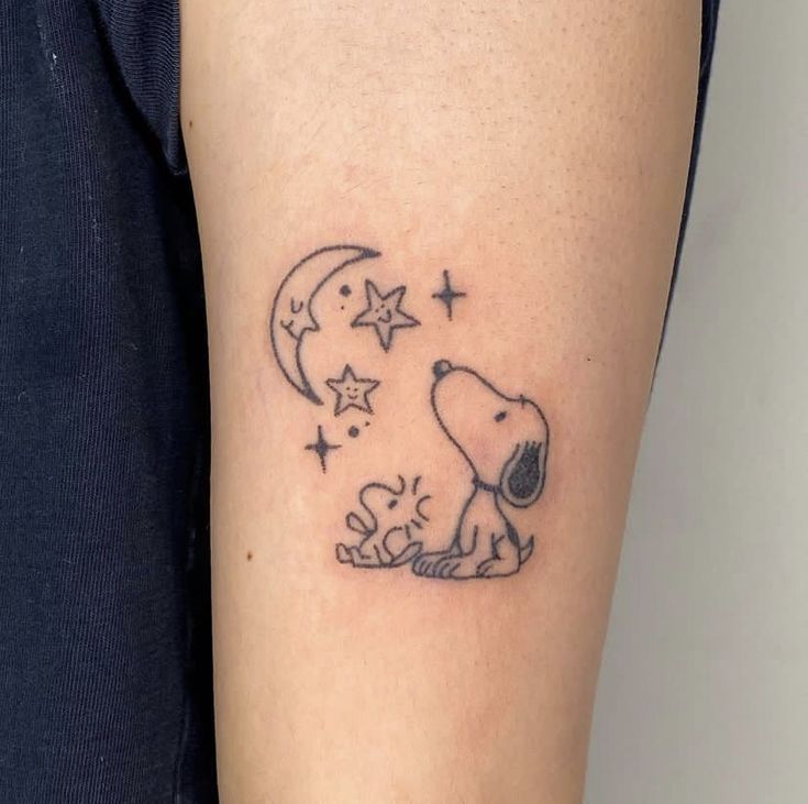 a small tattoo of a dog sitting on the ground with stars and moon above it