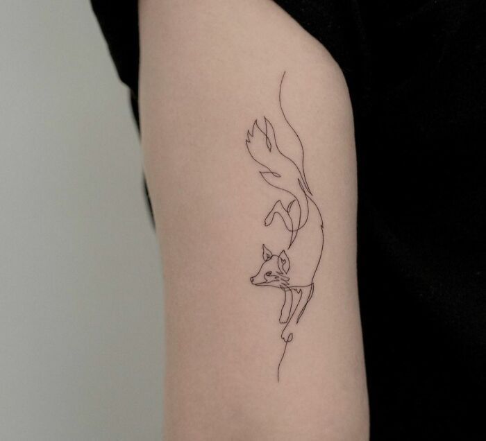 a woman's arm with a small tattoo of a fox and a bird on it