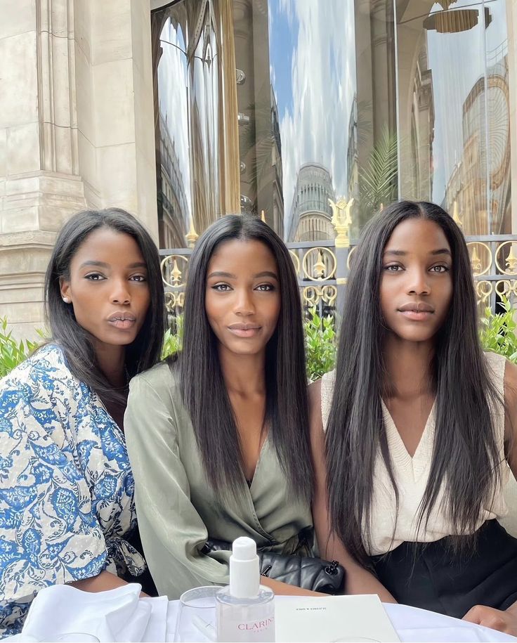 three women are sitting at a table outside