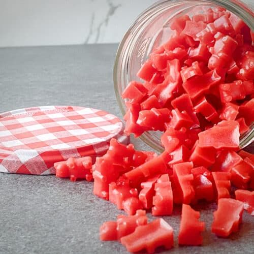 a jar filled with diced red food on top of a counter next to a paper plate